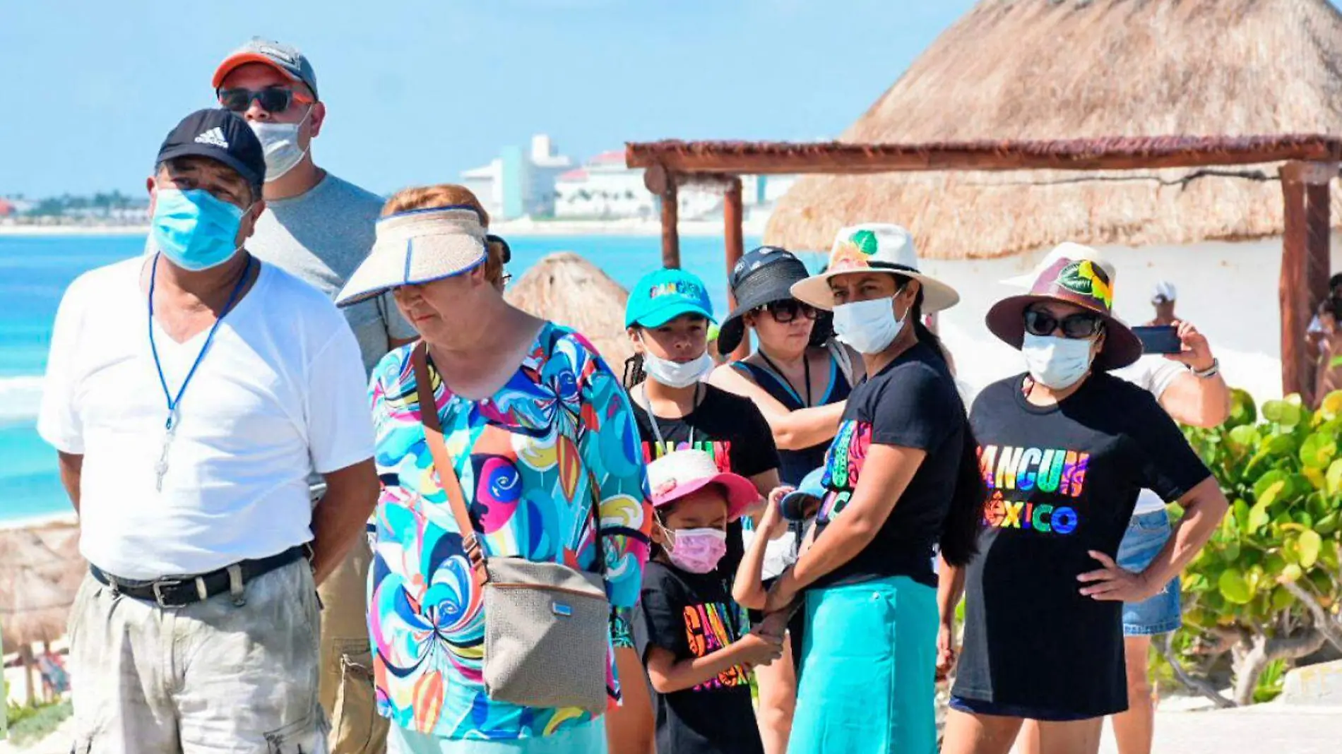 personas con cubrebocas en la playa